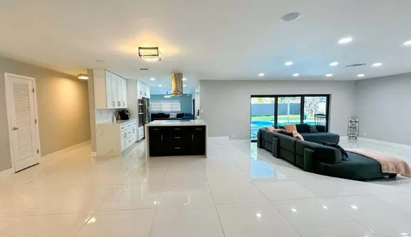 a large white kitchen with a large counter top a sink a stove and a refrigerator