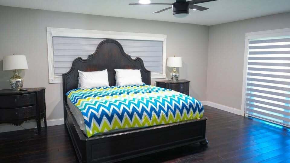 7410 Southwest 15th Street Plantation, FL 33317 - Photo 10 of 14 a bed sitting in a bedroom next to a lamp on dresser and a wooden floor