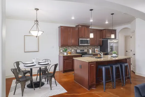 a kitchen with kitchen island granite countertop a table and chairs in it