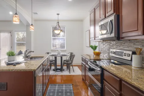 a kitchen with granite countertop a stove a sink a dining table and chairs