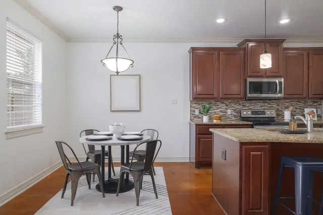 a kitchen with stainless steel appliances granite countertop a stove a sink a microwave a dining table and chairs