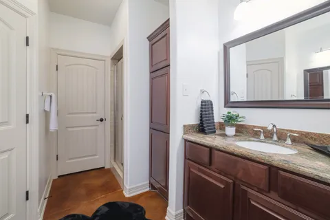 a en suite bathroom with a granite countertop sink and a mirror