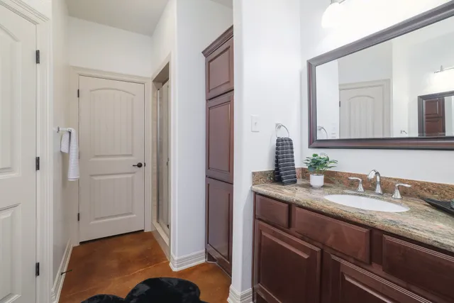 a en suite bathroom with a granite countertop sink and a mirror