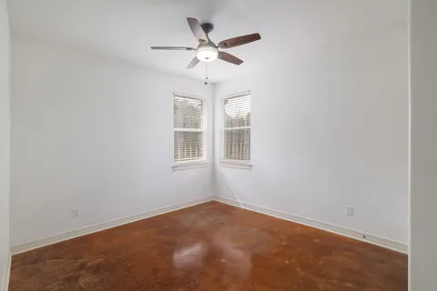 an empty room with window and ceiling fan