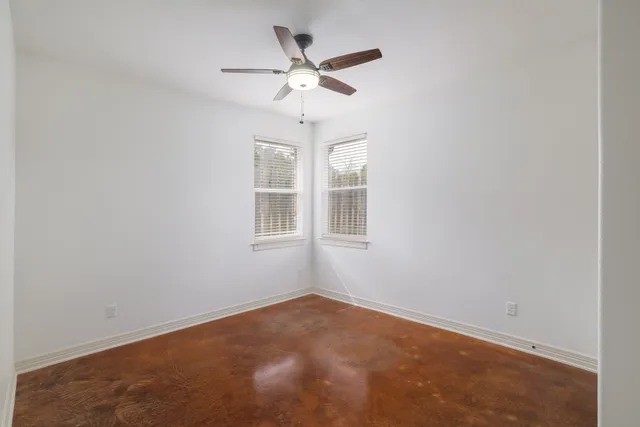 an empty room with window and ceiling fan