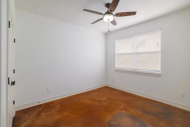 an empty room with a window and a fan