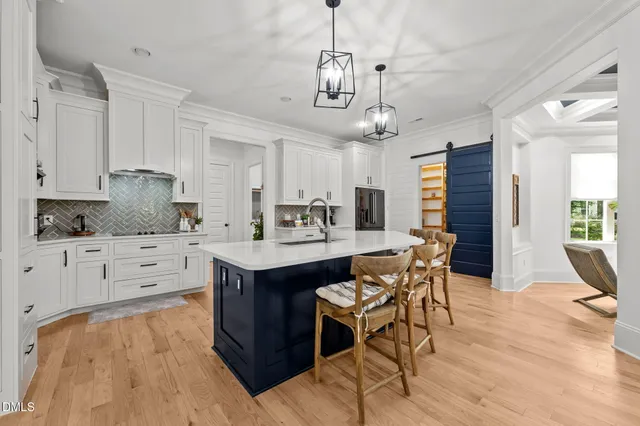 a open kitchen with stainless steel appliances granite countertop a sink dishwasher and white cabinets with wooden floor