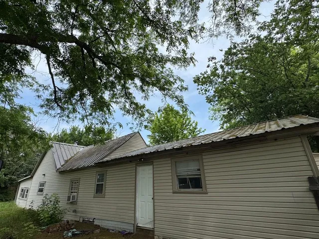 a side view of a house with a tree