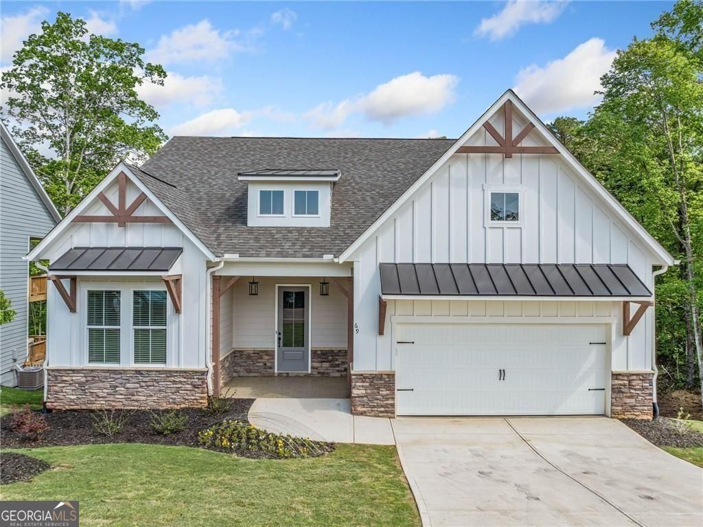 View of front of home with roof with shingles, stone siding, board and batten siding, driveway, and a standing seam roof