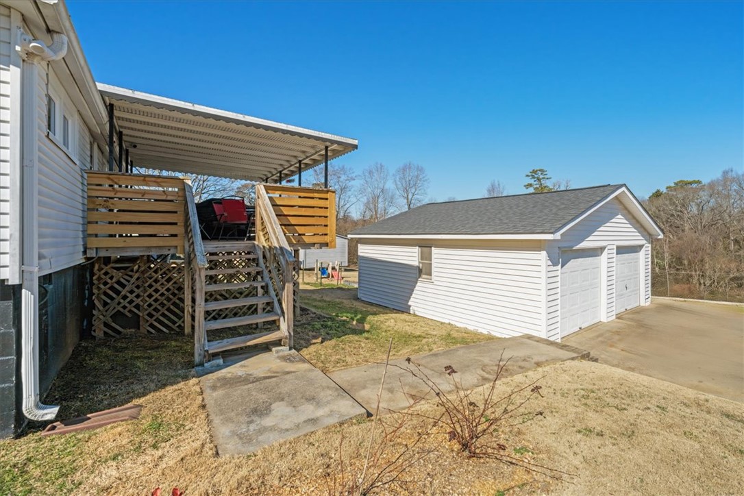 6 Fuller Street Pelzer, SC 29669 - Photo 28 of 36 This property features an inviting deck with stairs, perfect for outdoor relaxation, alongside a detached garage.
