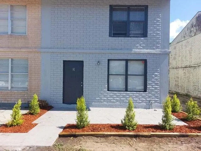 a front view of a house with a yard and potted plants