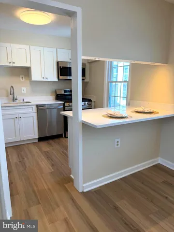 a kitchen with stainless steel appliances granite countertop a sink a stove cabinets and wooden floor