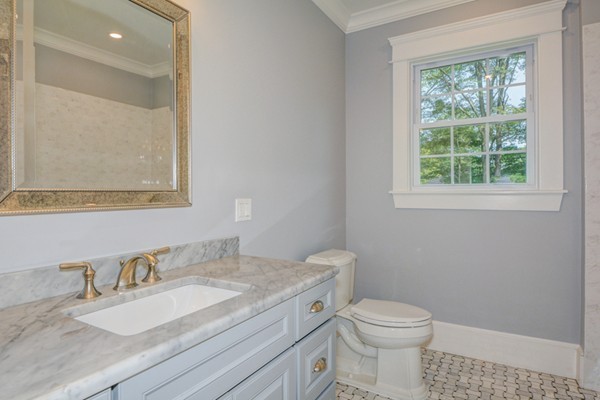 234 Langley Road Newton, MA 02459 - Photo 21 of 25 a bathroom with a granite countertop toilet a sink a mirror and a window