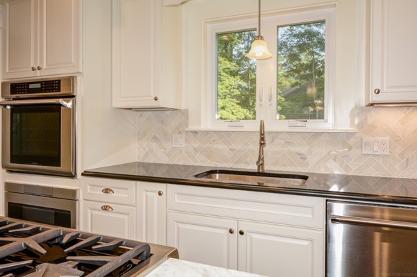 234 Langley Road Newton, MA 02459 - Photo 8 of 25 a kitchen with stainless steel appliances white cabinets and a window