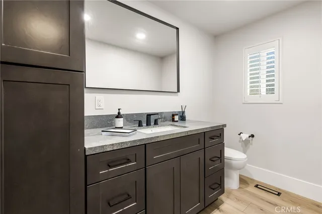 a bathroom with a granite countertop sink a toilet and a mirror