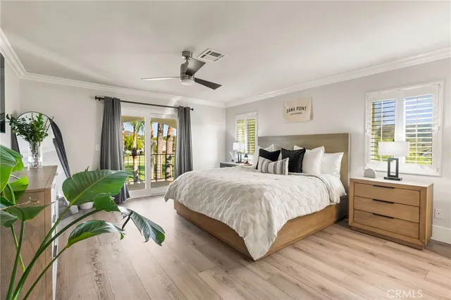 a bedroom with a bed and a large window with wooden floor