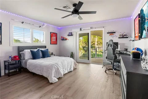 a bedroom with a bed a desk and chair with wooden floor