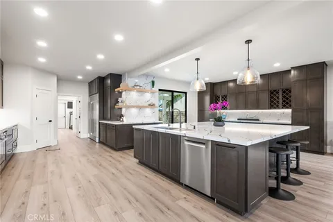 a kitchen with stainless steel appliances kitchen island hardwood floor sink stove and wooden cabinets