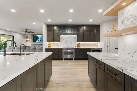 a large kitchen with stainless steel appliances a large counter top a sink and a refrigerator