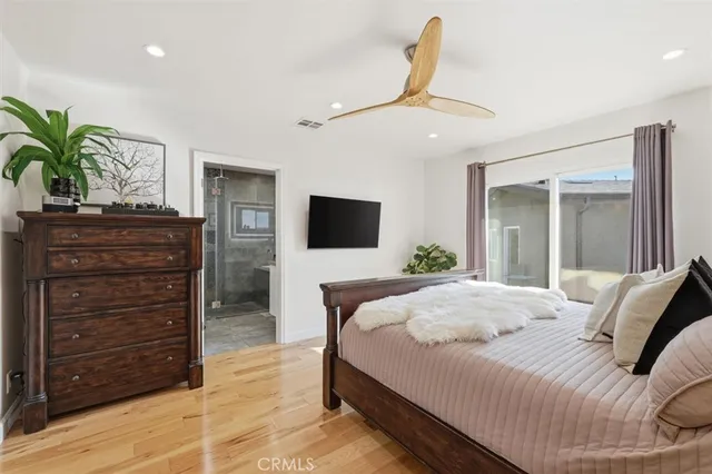 a bedroom with a bed a dresser and flat screen tv