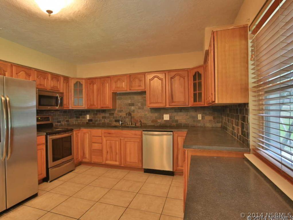 2738 Letha Road New Smyrna Beach, FL 32168 - Photo 4 of 21 a kitchen with stainless steel appliances granite countertop a stove a sink and a microwave