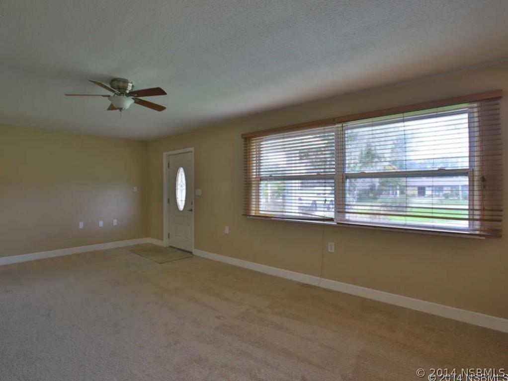 2738 Letha Road New Smyrna Beach, FL 32168 - Photo 7 of 21 an empty room with chandelier fan and windows