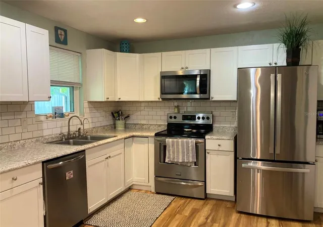 a kitchen with a refrigerator a microwave a sink and cabinets