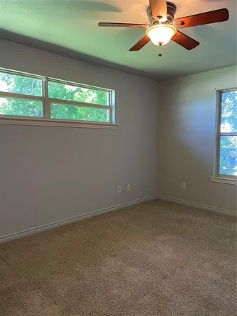 en empty room with windows and chandelier fan