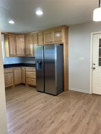 a view of a kitchen with a refrigerator and wooden floor