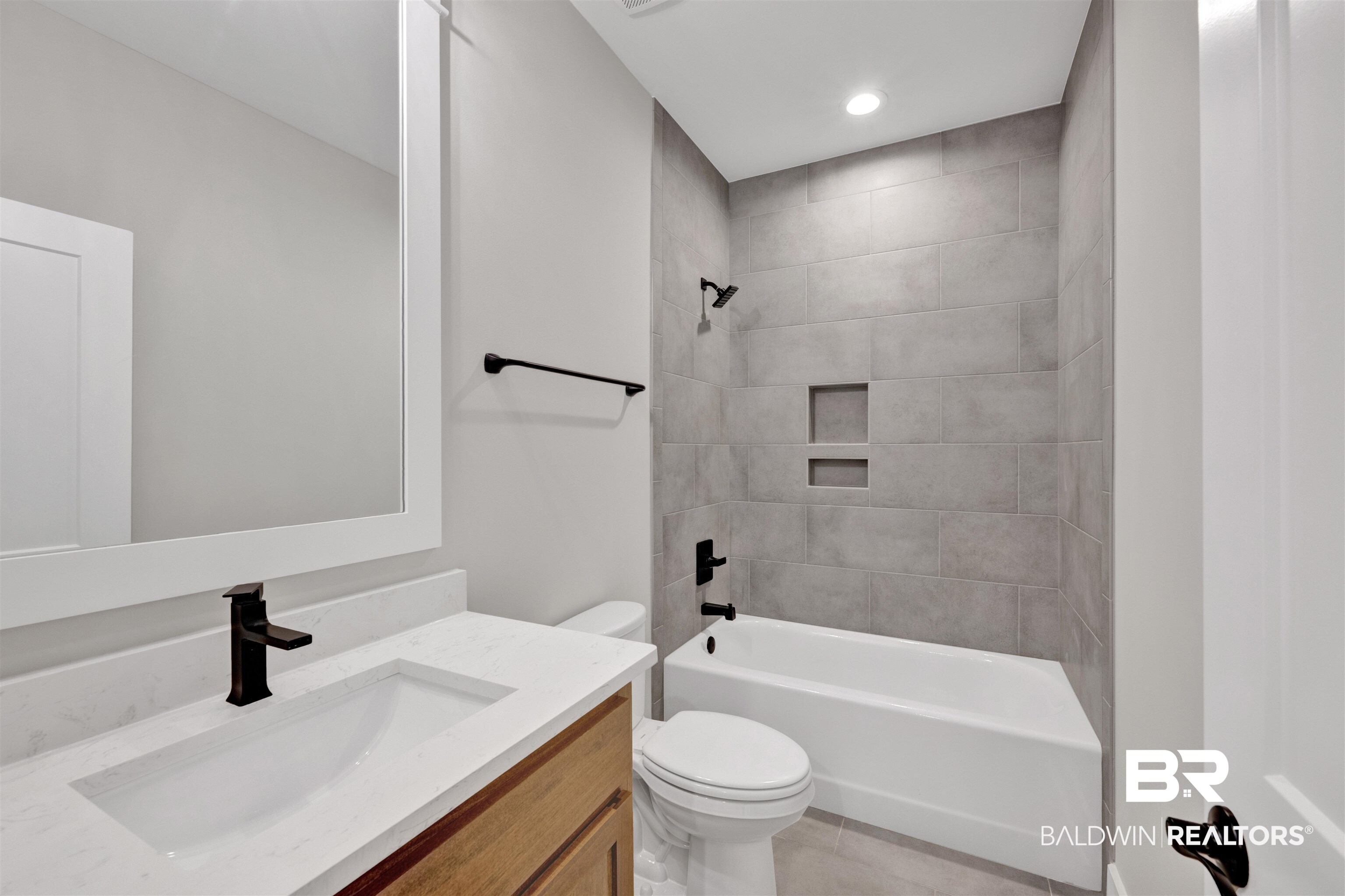 27371 Patch Pl Loop Daphne, AL 36526 - Photo 51 of 63 Bathroom featuring a white framed mirror, a vanity with a white countertop and undermount sink, matte black fixtures, a tiled shower/tub combination with built-in niches, and a recessed ceiling light