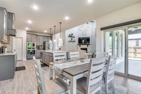 a kitchen with stainless steel appliances kitchen island granite countertop a table chairs sink and cabinets