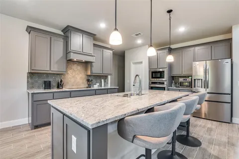 a kitchen with granite countertop a table chairs stainless steel appliances and wooden floor