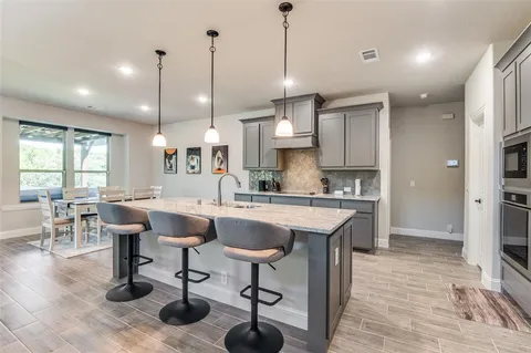 a kitchen with kitchen island granite countertop a sink a counter space appliances and cabinets
