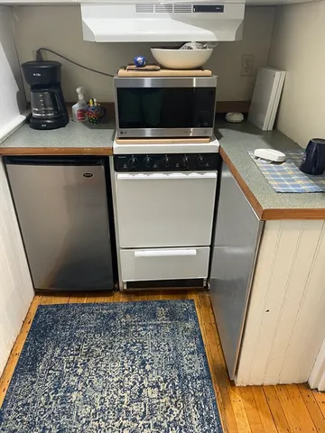 a kitchen with a stove and wooden floor