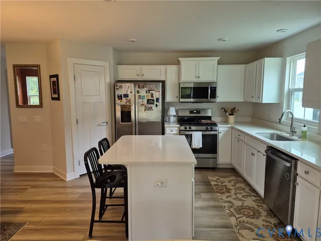 a kitchen with granite countertop a stove a sink a dining table and chairs