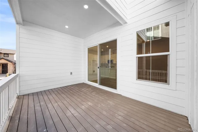 a view of an empty room with wooden floor and a kitchen