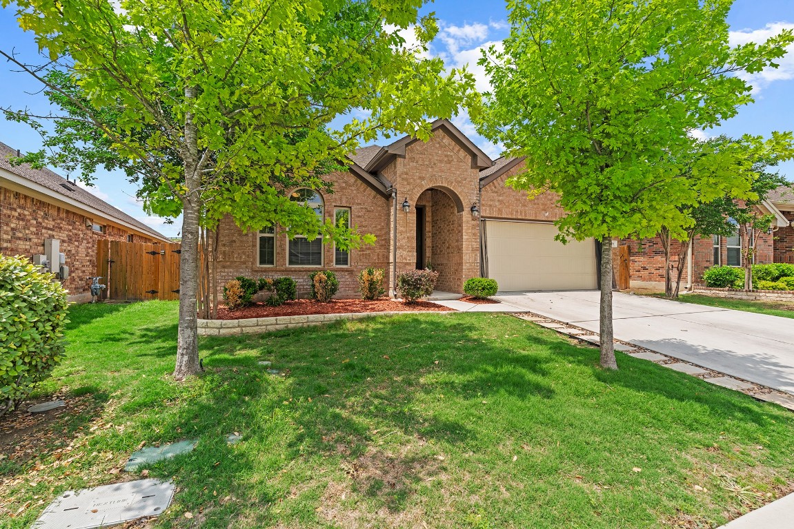 Traditional home with brick siding, fence, a garage, driveway, and a front lawn