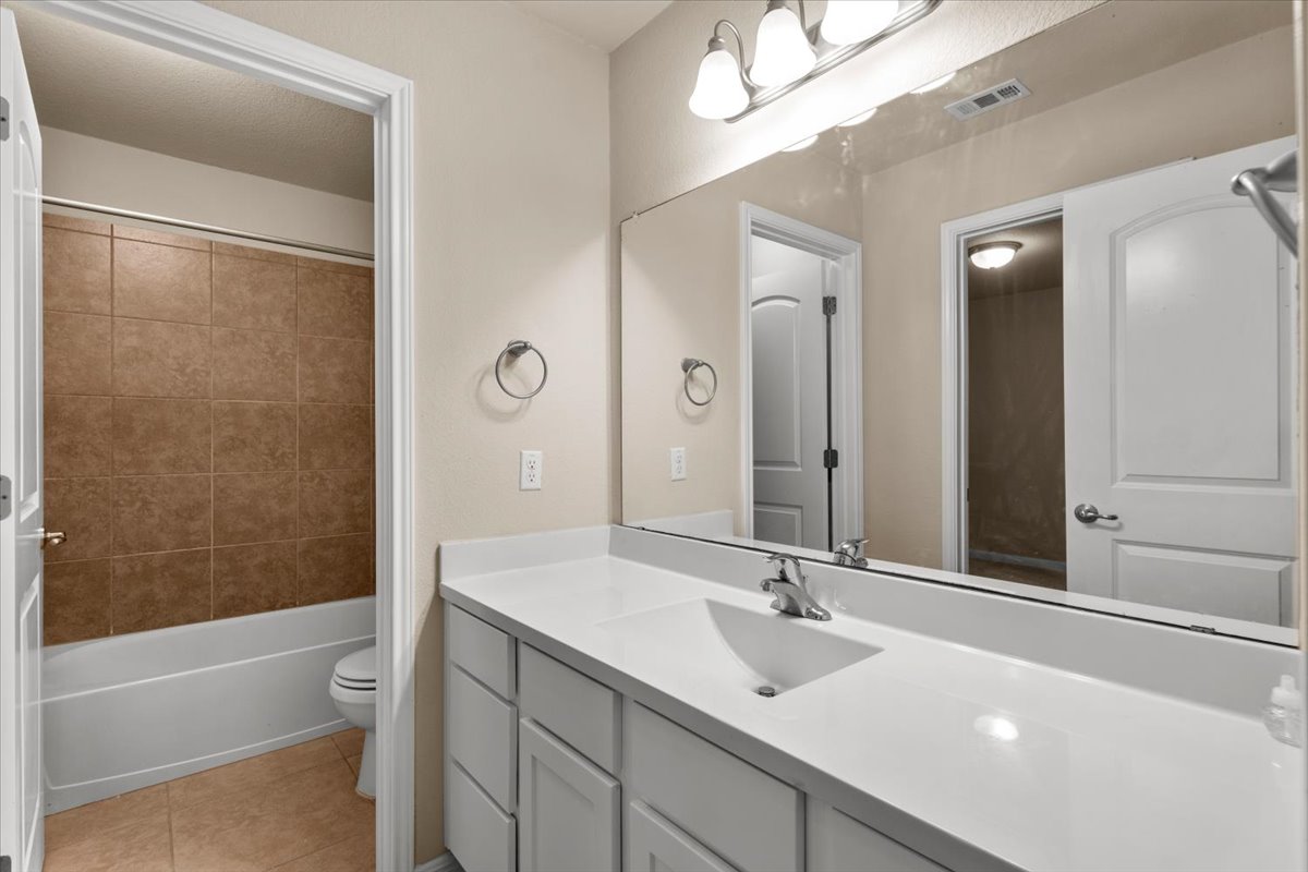 3451 Mayfield Ranch Boulevard, Unit 311 Round Rock, TX 78681 - Photo 27 of 40 Bathroom featuring a white vanity with an integrated sink, polished chrome faucet, and expansive mirror