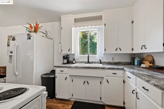 a kitchen with granite countertop white cabinets and white appliances