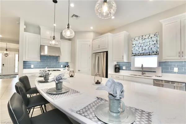 a large white kitchen with a large window a sink and white appliances