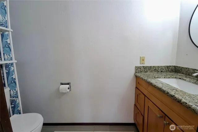 a bathroom with a granite countertop sink and a toilet