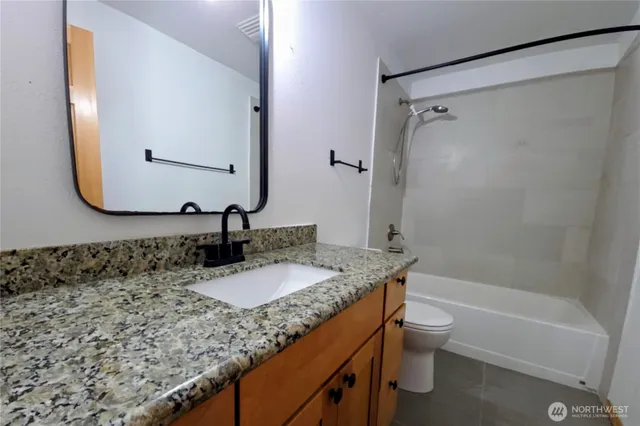 a bathroom with a granite countertop sink toilet and shower