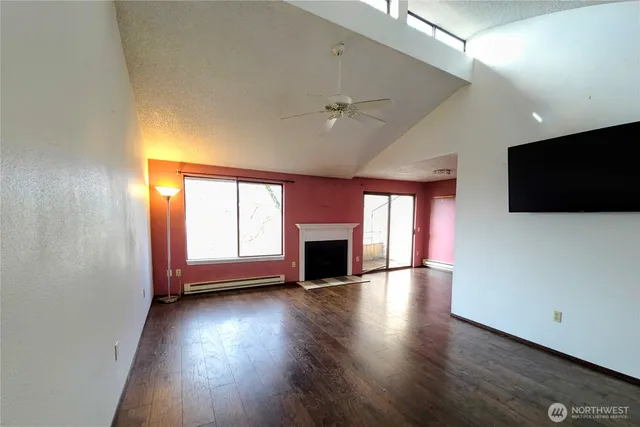 an empty room with wooden floor fireplace and windows