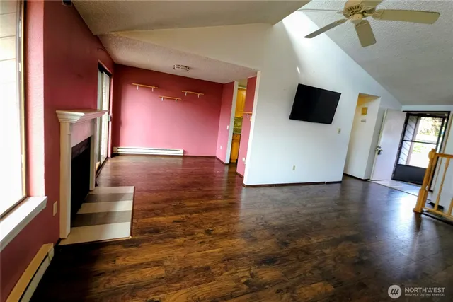 a view of empty room with wooden floor and fan