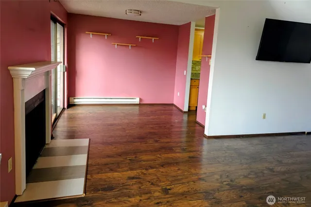 a view of an empty room with wooden floor and a fireplace