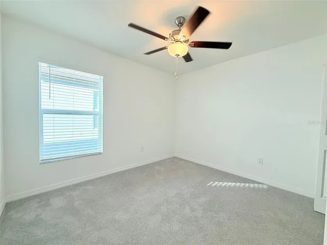 an empty room with a window and a ceiling fan