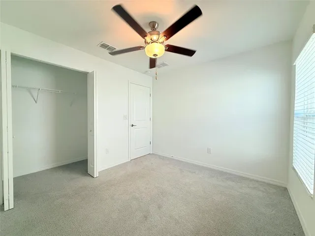 an empty room with a window and a fan