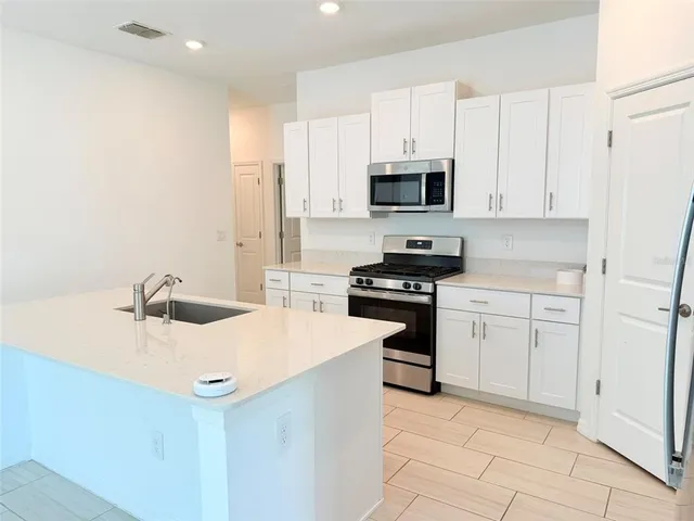 a kitchen with white cabinets and appliances