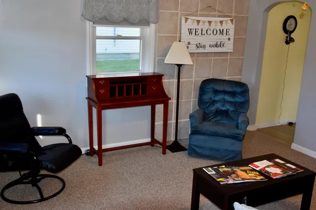 a bedroom with a bed two window and a lamp