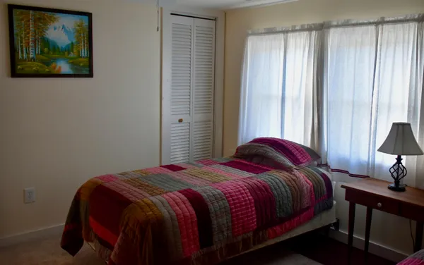 a bedroom with a bed two window and a lamp